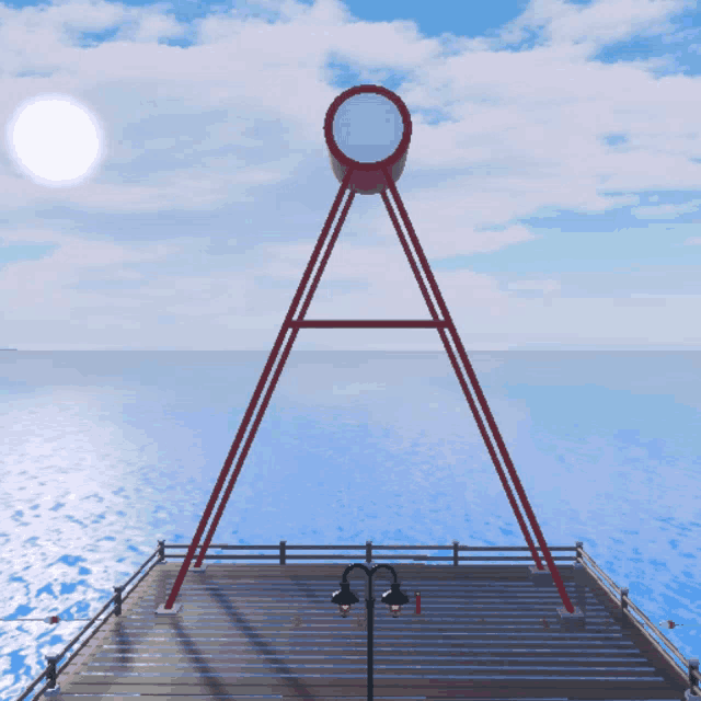 a large red object with a circle in the middle sits on a pier overlooking the ocean