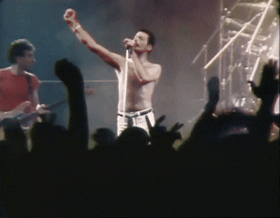 a shirtless man singing into a microphone with his fist in the air