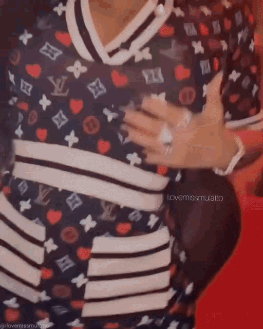 a woman in a louis vuitton dress is covering her chest with her hand .