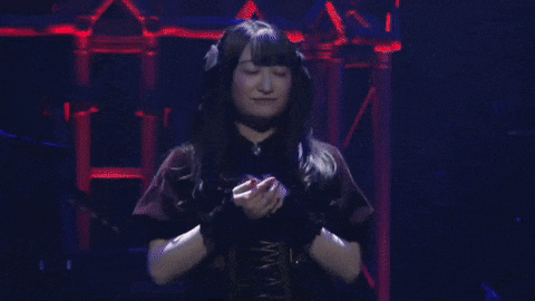 a girl with a choker around her neck is dancing on a stage with her arms outstretched