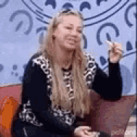 a woman is sitting on a couch holding a remote control .