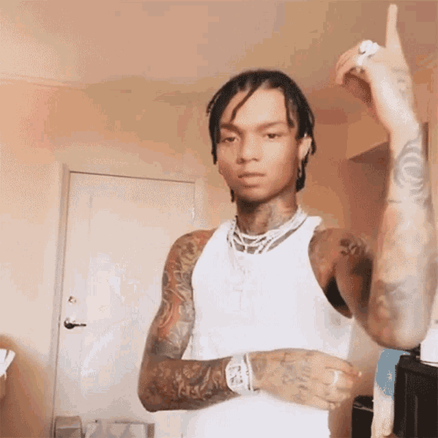 a man with a lot of tattoos is wearing a white tank top