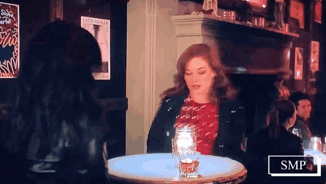 a woman sits at a table in front of a poster that says shine on the world