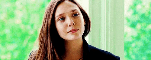 a close up of a woman 's face with long brown hair looking at the camera .