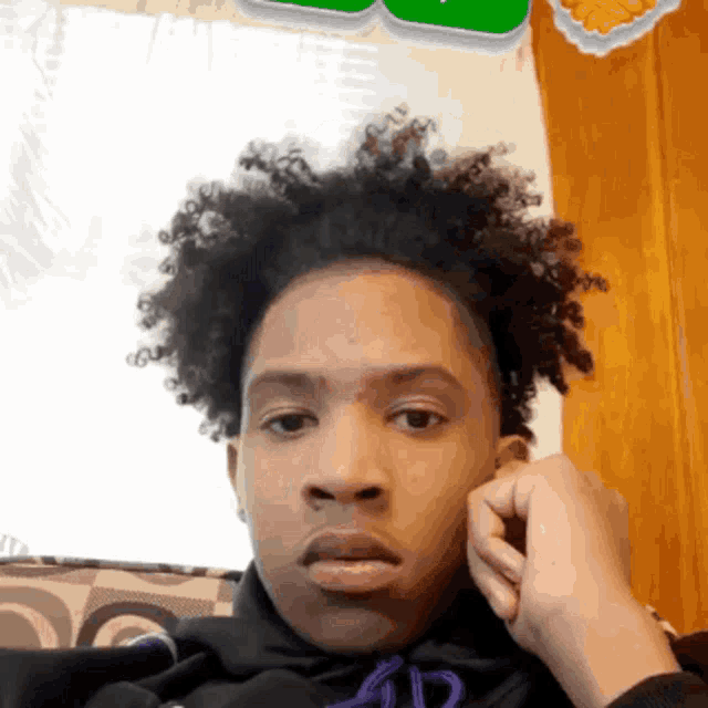 a young man with curly hair looks at the camera