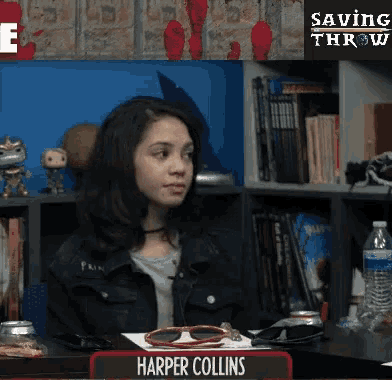 a woman sits at a table with a name plate that says harper collins