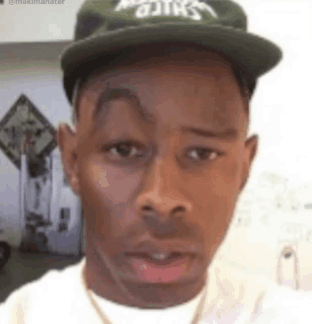 a close up of a man wearing a hat and a white shirt .