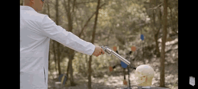 a man in a lab coat is holding a gun in front of a skull