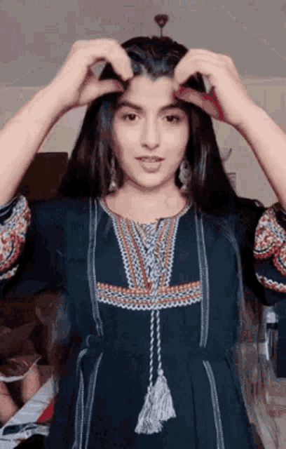 a woman in a blue dress is making a heart shape with her hands .