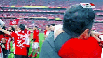 a man taking a picture of a group of soccer players wearing red shirts with the number 32 on them