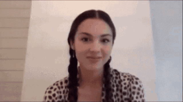 a woman in a leopard print shirt and braids is smiling .
