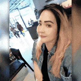 a woman wearing a denim jacket and a black shirt takes a selfie