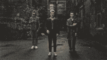 a black and white photo of three men in suits standing in an alleyway