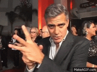 a man in a suit is making a funny face while standing in front of a crowd .