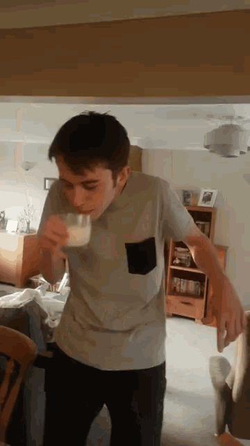 a young man is drinking a glass of milk in a living room