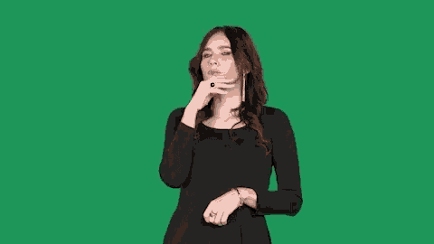 a woman in a black dress holds her hand to her chin