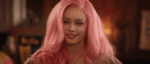 a woman with pink hair is smiling for the camera .