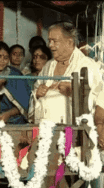 a man in a white robe sits in front of a crowd of people