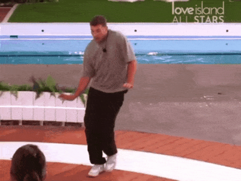 a man is dancing in front of a sign that says love island all stars .