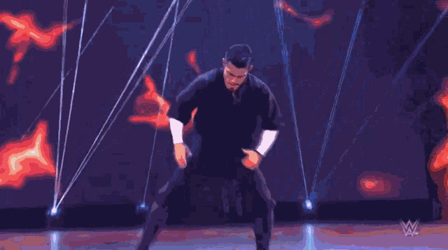 a man in a black shirt is dancing in front of a purple and red background