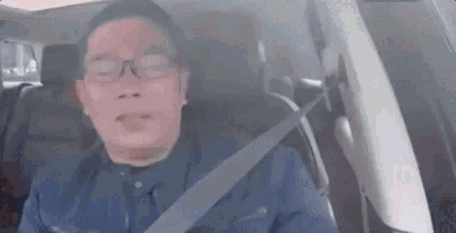 a man is sitting in the back seat of a car with his eyes closed .