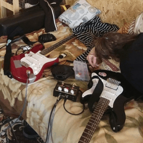a person laying on a bed with guitars and a pillow that says atlantic club