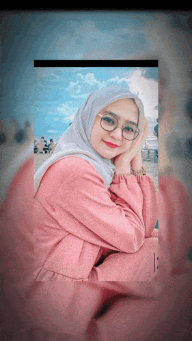 a woman wearing glasses and a hijab looks at the camera with her hands on her face