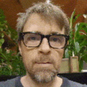 a man with glasses and a beard is wearing a gray shirt