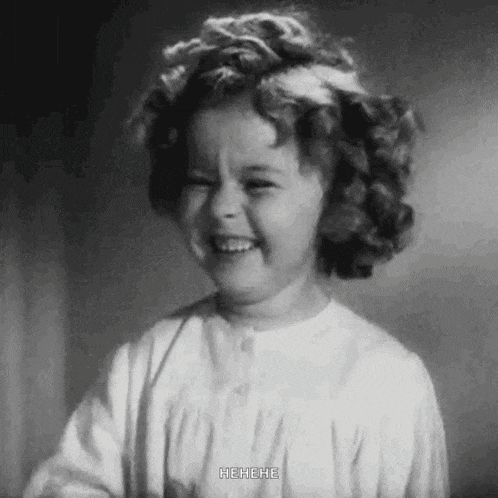 a little girl is smiling in a black and white photo .
