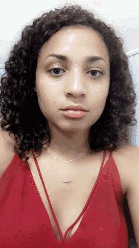 a woman with curly hair is wearing a red dress