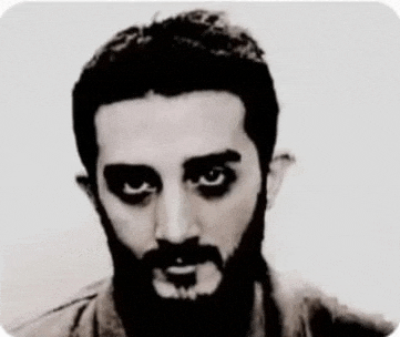 a man with a beard and black eyes is looking at the camera