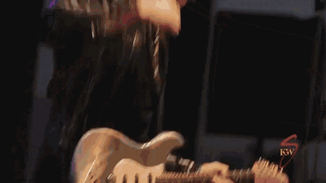 a man is playing a guitar in front of a microphone with the letters kw on the bottom right