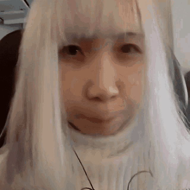 a close up of a woman with white hair making a funny face .