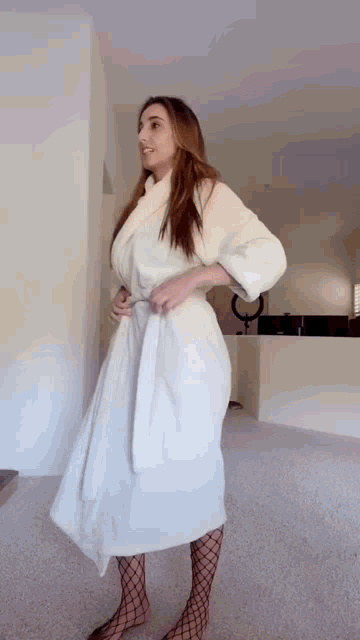 a woman in a white robe and fishnet stockings is standing in a room