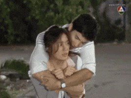 a man is carrying a woman on his back and kissing her .