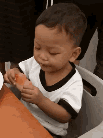 a little boy sitting at a table eating a piece of cake