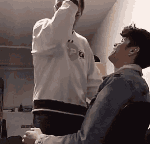 two men are standing next to each other in a room . one of the men is holding the other 's arm .