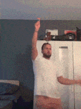 a man in a white t-shirt is dancing in a room