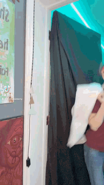 a person holding a pillow in front of a sign that says ' tik tok ' on it