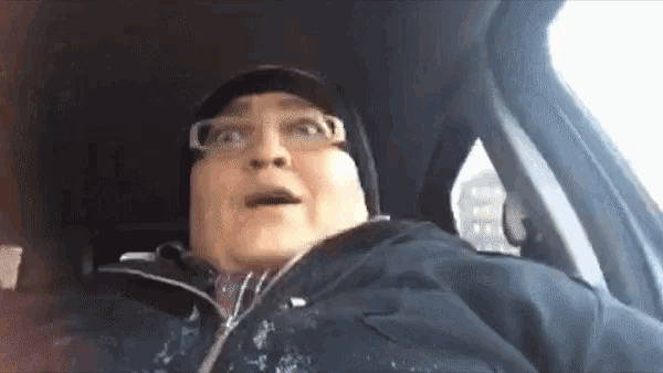 a man wearing glasses and a beanie is sitting in a car