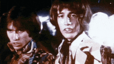 two young men are standing next to each other in a dark room .