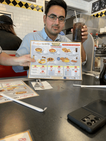 a man holds up a menu at a restaurant that says breakfast favorites