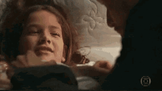 a little girl is laying on a bed with a man holding her .