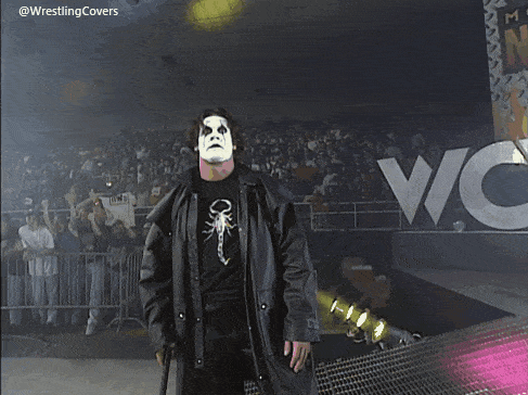 a man in a black coat is holding a sword in front of a crowd and the words @wrestlingcovers are on the bottom