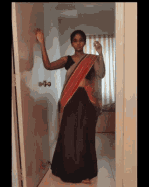 a woman in a saree is standing in front of a door