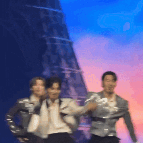 a group of men are dancing on a stage with a building in the background