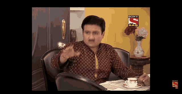 a man sits at a table with a sony sab logo on the bottom