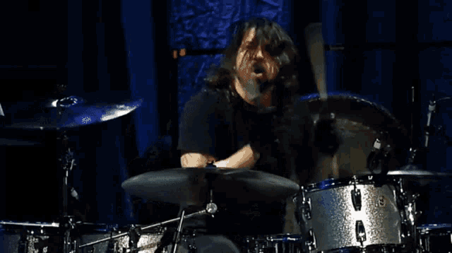 a man in a black shirt is playing a drum set