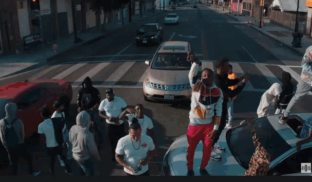 a group of people are standing on top of a car in a street