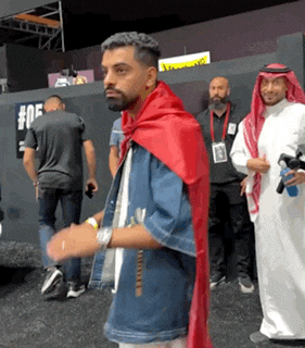 a man wearing a red cape is standing in front of a group of men .